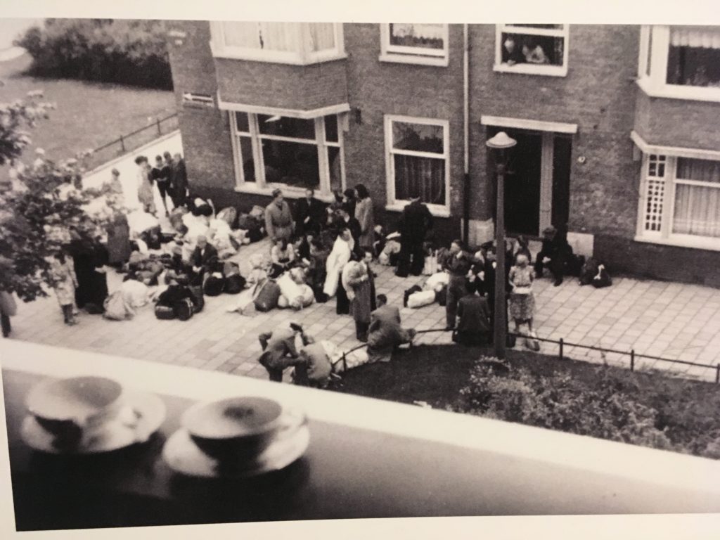 Bystanders with cups of tea on windowsill Lekstraat